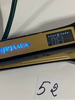 Close up photo of gold and black Wavytalk hair straightener showing digital LCD display with temperature reading.