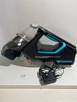 Side view of the Pet Stain Eraser PowerBrush carpet cleaner with charger cable placed in front.