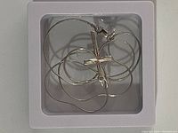 Silver cross pendant on a thin silver snake chain necklace, shown in a white display box with a lobster clasp.