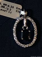 Close-up photo of the silver pendant with clear cubic zirconia stones arranged in an oval surrounding the dark garnet gemstone center.