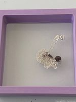 The necklace chain loosely arranged in a jewelry box showing the clasp and pendant.