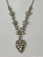 Full view of silver-tone necklace showing chain with crystal clusters and ornate faux pearl pendant