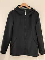Black fall/spring hooded jacket front view showing full zipper, hood, and zippered pockets