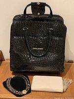 Front view of black David Jones travel bag with croc pattern, Deux Lux wallet, and silver-tone chunky necklace on display