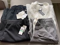 Set of four new ladies clothing items with tags including black linen pants, black modal pants, houndstooth pants, and white sheer jacket