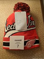 Red Detroit Red Wings touque with pom pom and NHL tag, folded showing logo and text