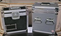 Photo showing black and grey flight cases side by side on a piece of furniture.