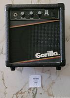Front view of Gorilla GG10 guitar practice amplifier showing control knobs, input jack, and Gorilla logo with diagonal stripes on the speaker grille.