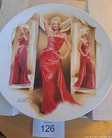 Front side of Marilyn Monroe collectors plate showing her in red dress from movie "How to Marry a Millionaire"