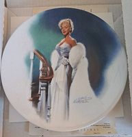 Collectors plate showing Marilyn Monroe in white fur stole and evening gown by staircase, image signed Chris Nohrtle