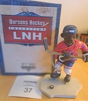 Photo of the NHL collectible hockey bear figurine on its base with puck, showing the front view with the box in background