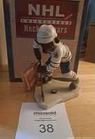 Front angled view of the hockey bear figurine showing the bear in Toronto Maple Leafs uniform with the box behind it.