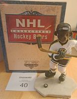 Front view of NHL Collectible Hockey Bear figurine in Boston Bruins uniform with box in background showing branding and condition.