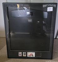 Front view of the sports jersey display case showing clear glass front and three small memorabilia windows at the bottom.