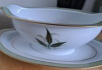 Side view of vintage Noritake porcelain gravy boat showing green leaf pattern and gold trim.