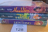 Side view of three stacked Walt Disney Classics VHS tapes: Aladdin on top, The Fox and the Hound in the middle, The Lion King on bottom.