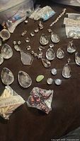 Overhead view of mixed chandelier crystal pieces in various shapes and small loose beads on a black fabric background, including packaged beads