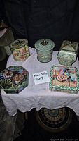 Five tins on a table including three antique English tins, Disney Christmas Mickey & Minnie Mouse tin, and an octagonal jungle animal tin.