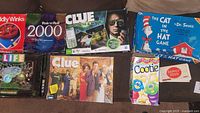 Photo showing multiple boxed classic family board games including Life, Clue, Cootie, Risk 'n' Roll, The Cat in the Hat, and others.