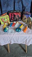 Photo showing full collection of lunch boxes and PEZ dispensers on a white cloth with blue backdrop.