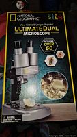 Photo of product box showing National Geographic branding and Ultimate Dual Microscope with over 50 accessories label