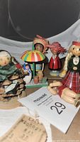 Close-up showing variety of antique and vintage wooden toy dolls with colorful clothing, yarn hair, and umbrella accessory.