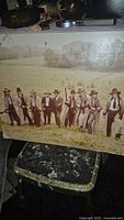 Poster-board photograph of The Long Riders cast, sepia tone, 9 men in western attire outdoors.