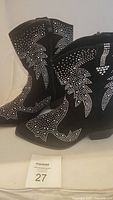 Pair of black suede short cowboy boots with rhinestone patterns visible on sides and front. Boots are pointed toe style with low heel, outside loop pull and an inner full-length zipper.