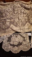 Close-up of large square lace tablecloth with floral and ornamental pattern detail