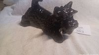 Side angle view of glossy black porcelain Scottish Terrier figurine showing body and tail detail.