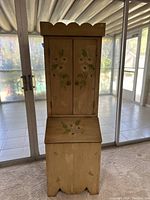 View of lower section with drop front panel showing floral painting.