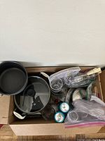 Top view showing large pot with glass lid, smaller black saucepan, glassware, and various utensils.