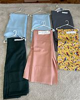 Overview of six assorted table linens on hangers showing colors and sizes