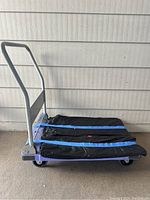 Side view of large purple furniture dolly with blue straps and black pad secured on base.