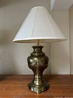 Full view of Roman style bronze table lamp with white fabric shade, showing the urn-shaped body and conical lampshade.