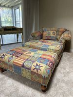 Shows the vintage-style armchair and ottoman set in a room, highlighting the colorful geometric patterned upholstery and wooden legs