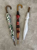 Full view of the three vintage umbrellas showing their handles and folded canopies.