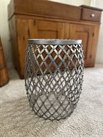 Side view of the metal stool showing woven lattice metal design and cylindrical shape.
