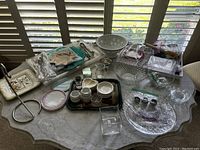 Overview of various glassware, ceramics, trays, and packaged electric blankets on a marble surface
