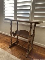 Front and side angle view showing the end table's turned legs and lower shelf, highlighting the wood finish and slight wear.