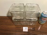 Three clear glass refrigerator dishes with lids stacked, next to a soda can for scale.