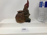 Front and side view of a circa 1910 redware ceramic bank depicting a gnome holding a bag, showing details of the figure and bag.