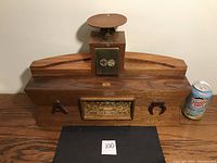 Full view of wooden Eucharist box with brass door and curved base, alongside a soda can for size reference.