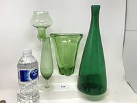 Front view of all four green glass items with water bottle for scale