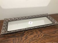 Top view of rectangular mirrored tray showing reflective glass and ornate floral frame