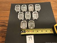 Nine small rectangular clear glass salt cellars arranged on black background with measuring tape showing dimensions just over 2.5 inches wide.
