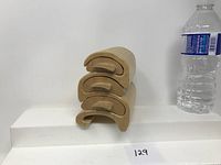 Four light wood treenware boxes stacked on top of each other. Bottled water on the side for scale.