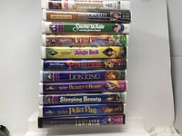 Eleven VHS tapes stacked with visible titles and Disney branding.