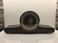 Front view of the vintage wooden mantel clock showing the rounded top and brass bezel around the clock face.