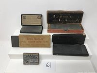 Photo showing 4 vintage/antique razor hones of different sizes and boxes, plus a metal razor blade sharpener tin.